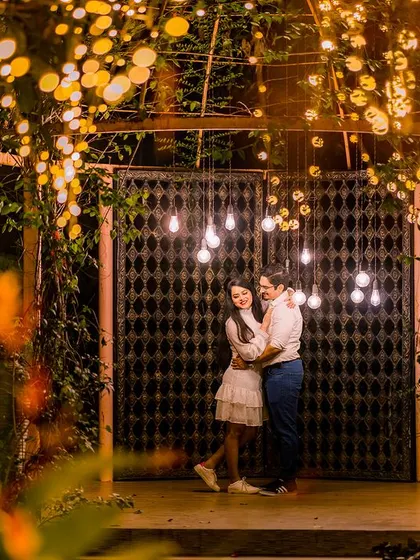 A wide shot showing the grand scale of the light-covered archway. The couple embraces underneath, creating a scene that is both epic and deeply romantic.