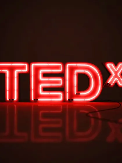 The iconic TEDx logo, a symbol of ideas worth spreading. For me, it represents the power of a single voice to spark change, a belief that I carry into every speaking engagement.