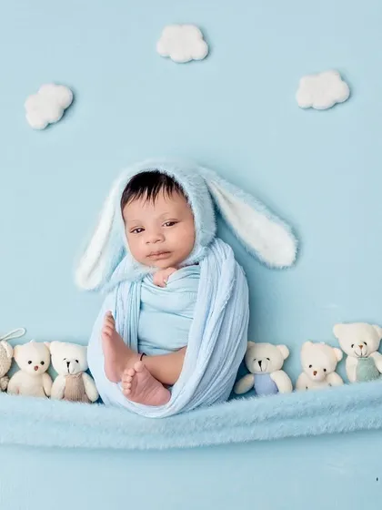 This little bunny is awake and looking right at the camera! The soft blue wrap and matching bunny ears create a sweet and cohesive look.