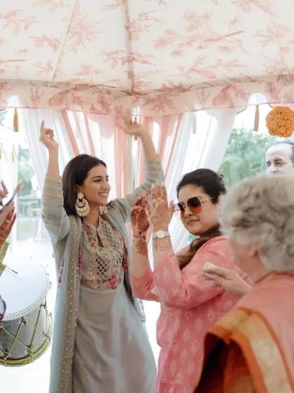 The bride dances with family under a custom-printed tent at her Chooda ceremony. We designed the space to be elegant and fun, creating a welcoming atmosphere for an intimate gathering.