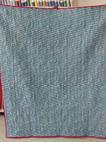 The back of the jelly roll race quilt, featuring a simple, textured blue fabric.