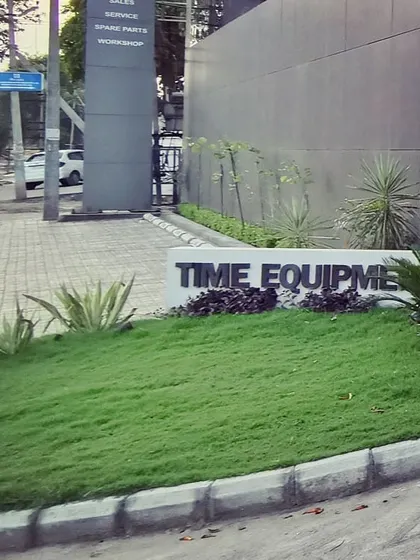 Landscaped signage for "Time Equipment" at the site's entrance. The use of raised lettering on a manicured grass mound creates an elegant and organic branding statement.