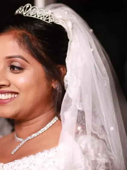A candid shot of the bride, smiling and radiant. The makeup is designed to enhance her natural beauty without looking heavy, perfect for a Christian wedding.