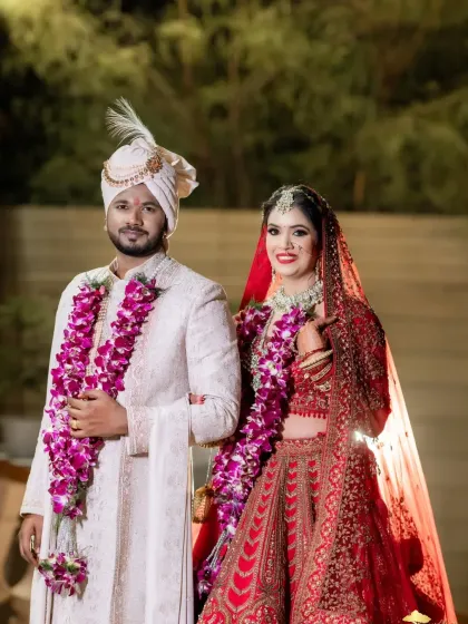 A classic full-length portrait of the bride and groom in their wedding attire.