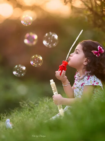 Lost in a world of bubbles. This beautiful, candid shot taken at sunset captures the simple joys of childhood in a serene and magical way.