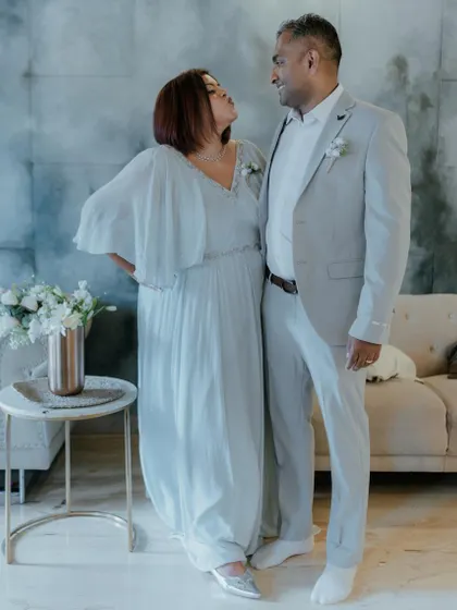A sweet moment between a couple in their coordinated attire. His light grey suit perfectly matches the soft blue of her custom-designed gown.