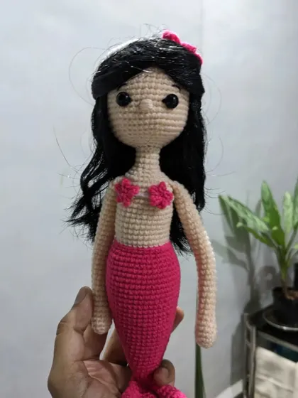 Holding the full mermaid doll to show her long, elegant body and tail.