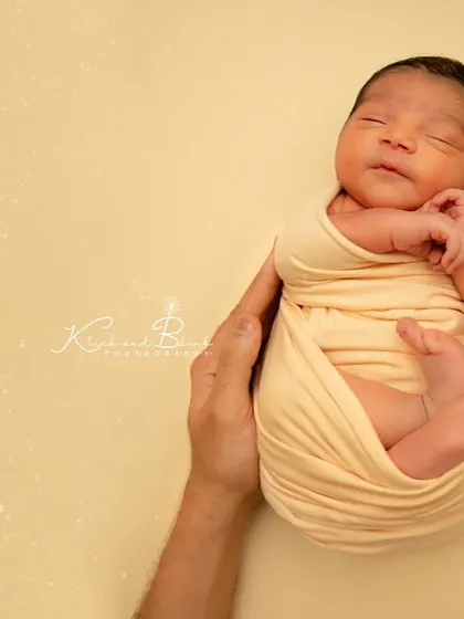 Another version of the "in your hands" pose, this time with a cream wrap against a warm yellow background. The simplicity is what makes it so powerful.