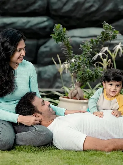 Relaxing together as a family. This candid shot captures a quiet, loving moment with the baby sitting happily on his father's chest during their outdoor portrait session.