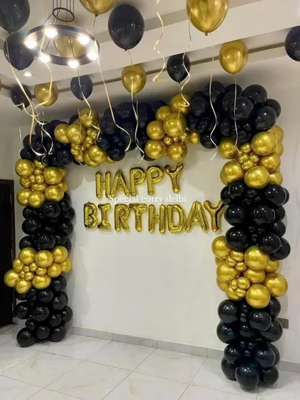 A classic and bold birthday decoration with a black and gold balloon arch and 'Happy Birthday' foil letters.