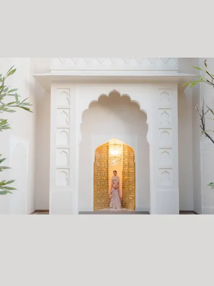 A wide shot that emphasizes scale and architecture. The bride stands as a regal figure within the grand archway, a perfect example of a fine art environmental portrait.
