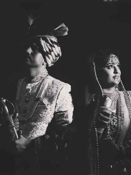 A powerful black and white portrait of the bride and groom in their traditional wedding attire, looking regal and timeless.