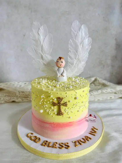 A baptism cake for little angel Ziva. This cake features a sweet yellow and pink ombre, a hand-sculpted angel, and delicate, edible wafer paper wings.