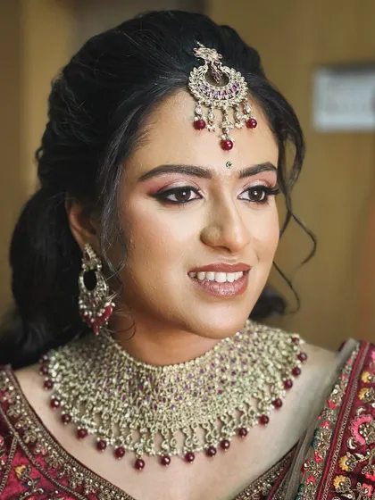 A close-up of the reception makeup. The shimmering pink and maroon tones on the eyes are perfectly coordinated with her lehenga and jewellery.