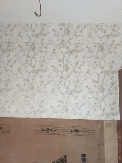 A delicate cherry blossom wallpaper being installed behind a headboard. The light and airy design brings a touch of spring and tranquility to the bedroom.