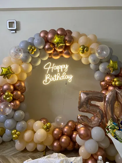 A full view of the elegant 50th birthday setup, showing the complete circular balloon arch and a small table for the cake.