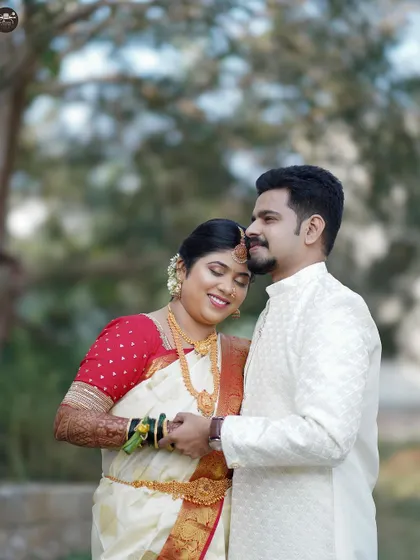 A gentle and affectionate portrait of a newly married couple outdoors. The groom embraces the bride from behind as she smiles with her eyes closed, capturing a moment of pure bliss.