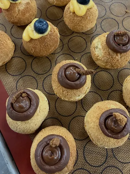 A close-up of my choux pastries being filled. You can see the different fillings, from a rich chocolate to a light pastry cream, each topped with a garnish.