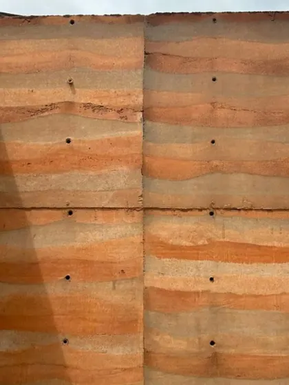 The panelled construction of a rammed earth wall, showing the seams and tie-rod holes that become part of its character.