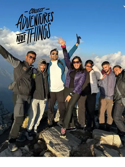Collect adventures, not things. A group of friends celebrating at a mountain summit, perfectly capturing the spirit of our travel philosophy.