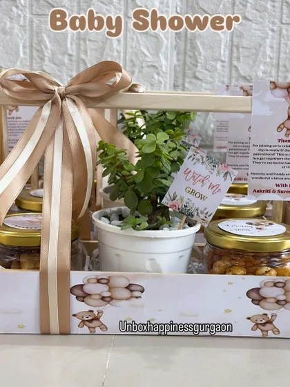 This baby shower favor features a beautiful jade plant with a "Watch me Grow" tag, paired with jars of snacks. It's a thoughtful, eco-conscious gift for guests.