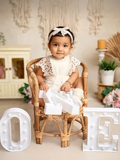 One year old and sitting like a queen. This portrait uses a beautiful rattan chair and light-up letters to create a stylish and memorable first birthday photo.