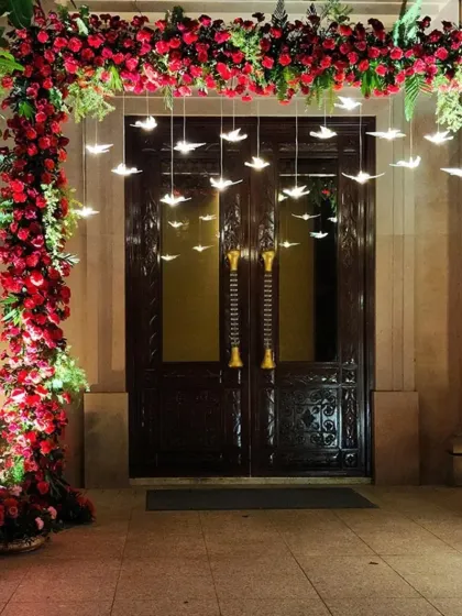 A stunning entrance arch made entirely of red roses with hanging bird lights. This creates a dramatic and romantic welcome for any special event.