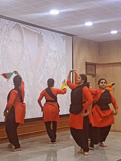 Dancers demonstrating a Lambani folk dance step, with a slide of traditional Lambani women in the background for context.