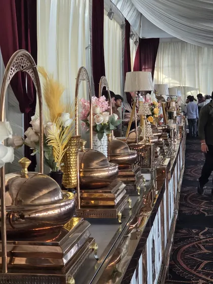 An elegant buffet line from a recent wedding we catered. The setup features our premium copper-toned chafing dishes, beautiful floral arrangements, and ambient table lamps, creating a warm and inviting dining experience for guests.