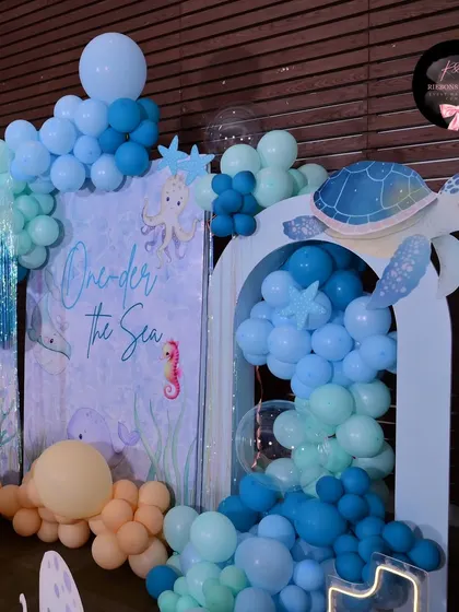 A close-up of the balloon work and turtle cutout prop from the 'One-der the Sea' theme. The different shades of blue balloons create a water-like effect.