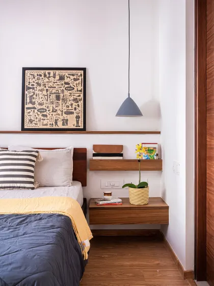 This bedroom from our 'Footloose' studio apartment project features a floating wooden nightstand and a minimalist pendant light. The design is simple, functional, and creates a cozy corner for rest.