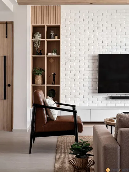 A modern entryway that opens into the living room. The design features a built-in wooden bookshelf next to the door and a comfortable leather accent chair, combining style with function.