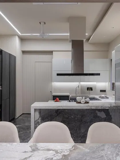 This shot from the dining area shows how the kitchen's design is integrated with the rest of the home. The fluted stone on the island front adds texture and connects with the sophisticated materials used in the living space.