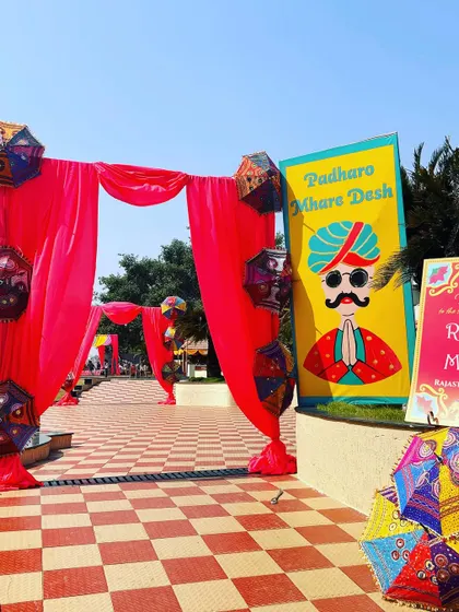 The entrance to a "Rajasthani Mela" themed event, with a quirky sign and colorful traditional umbrellas.
