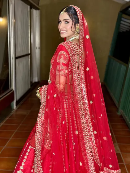 A beautiful shot from the back, showing the full effect of the red lehenga and dupatta. The makeup remains flawless from every angle.