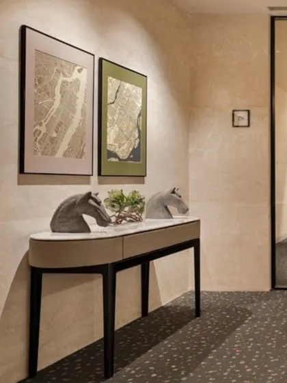 Art and decor are essential to a space's narrative. This console table arrangement in the Elevate Clubhouse features sculptural horse heads and framed map art, adding a layer of personality and sophistication to the transitional hallway space.