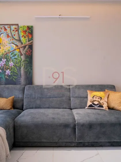 A cozy L-shaped sofa in grey, styled with quirky cushions and a piece of vibrant art, adding personality to the living space.