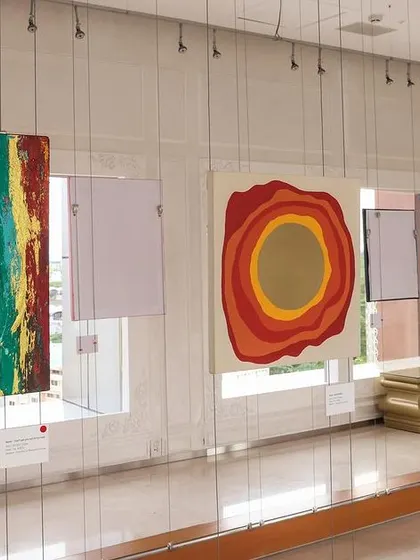 Another view of the 'Inner Tides' gallery, with colorful striped and circular abstract paintings.