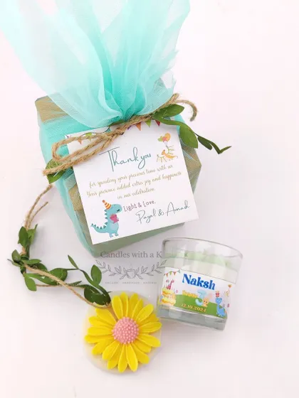 A close-up of the dinosaur-themed birthday gift. The personalized thank you card featuring a cute dinosaur adds a playful touch to the elegant candle and sachet.