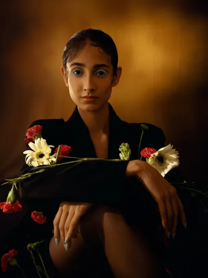 A seated portrait where flowers are integrated into the styling. The soft, directional light creates a classic, fine art feel.