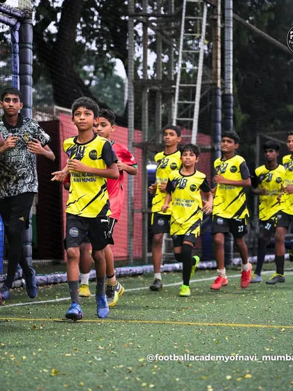 A team of players jogs across the pitch as part of their warm-up routine. I instill the importance of discipline and preparation from the very start of each session.