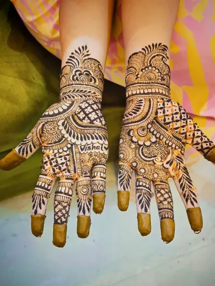 A palm-side design that heavily features jaali work on the fingers and palm, complemented by personalized elements.