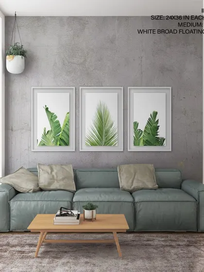 Another view of our three-piece tropical leaf set in an industrial-style living room. The white broad floating frames offer a clean, gallery-quality presentation that makes the artwork stand out.
