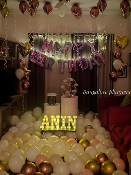 I can fill your home with balloons for an immersive birthday surprise. This living room setup features dozens of balloons on the floor, ceiling balloons, and light-up letters spelling the name "ANIN" for a fun and festive atmosphere.