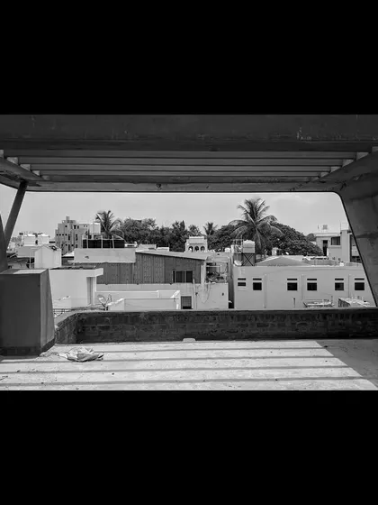 A view from an unfinished balcony, framing the surrounding urban landscape and capturing the patterns of light and shadow from the roof structure.
