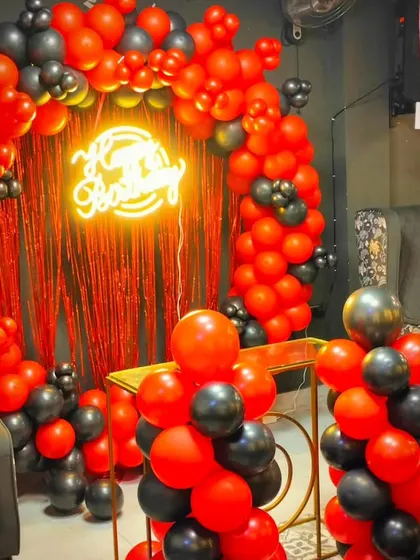 A close-up of the red and black balloon arch, showing the balloon pillars and the neon sign. This color combination is great for a modern and edgy celebration.