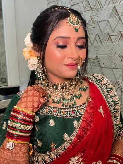 A close-up of Gauri's makeup, featuring shimmery eyeshadow, a traditional nath, and beautiful green stone jewellery.