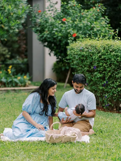 A family enjoying a picnic on the grass with their newborn. A relaxed and beautiful way to capture your first family photos.