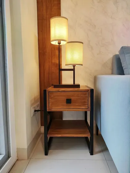 Details matter. This custom side table features an integrated two-tier lamp, providing both a surface for essentials and ambient lighting, all within a single, space-efficient piece with a metal and wood finish.