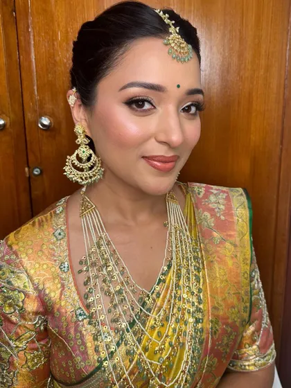 A close-up of the final look, with glowing skin, defined eyes, and beautiful layered jewelry.